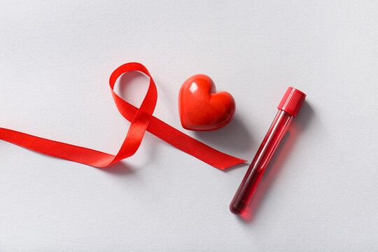 Red ribbon with heart and blood sample on grey background. Blood Cancer Awareness Month