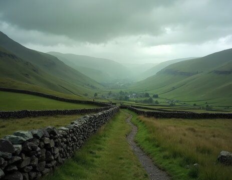 Green rolling hills and valleys with dry stone walls. A path leads through grassy fields towards a distant village under a cloudy sky. Rural English countryside landscape.