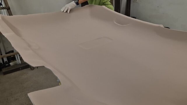 Car headliner fabric, auto interior installation, worker hands carefully smoothing beige textile in workshop for vehicle