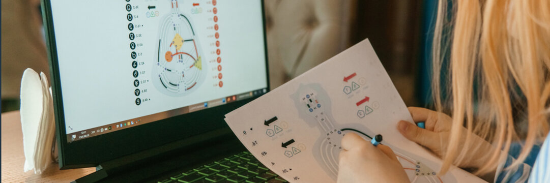 Tver, Russia-august 2, 2021. woman in cafe at table with laptop is studying design of person. concept of studying esoteric sciences. A red-haired woman with glasses studies a rave card by human design