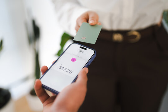 A person uses a mobile device to make a contactless payment with a credit card, showing a transaction of seventeen dollars and twenty-five cents.