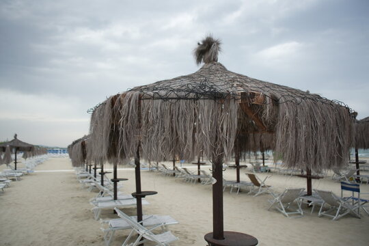 Beach in Giulianova with straw umbrellas and sunbeds, calm shore, soft sand, peaceful atmosphere, empty summer scene, seaside view.