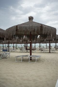 Beach in Giulianova with straw umbrellas and sunbeds, calm shore, soft sand, peaceful atmosphere, empty summer scene, seaside view.