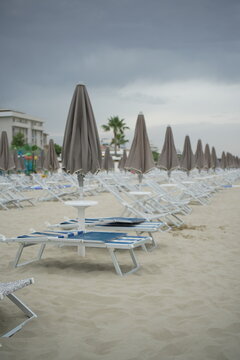 Beach in Giulianova with closed umbrellas and sunbeds, calm shore, soft sand, peaceful atmosphere, empty summer scene, seaside view.