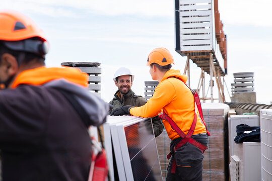 Engineer and worker talking during rooftop solar panel inspection