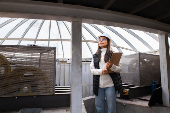 Engineer with safety helmet reviewing documents at construction site indoors