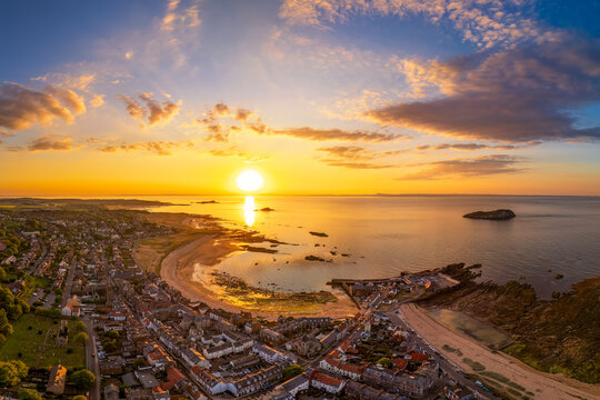 Drone aerial view of North Berwick harbor and coastline at sunset