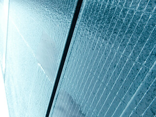 Detailed texture of ice and water droplets on a solar panel surface in winter.