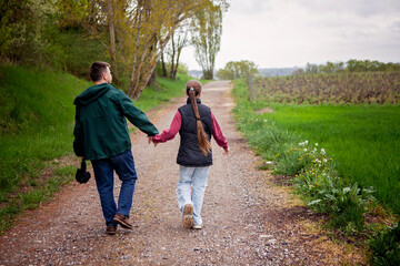Fototapeta premium Wide-angle lifestyle scene of a father and daughter walking in gentle rain. A soft and close moment of offline escape, quiet support, and slow living without rush or extremes.
