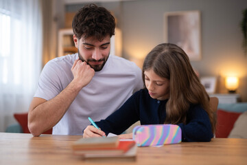 Fototapeta premium Father helping daughter with school homework at home