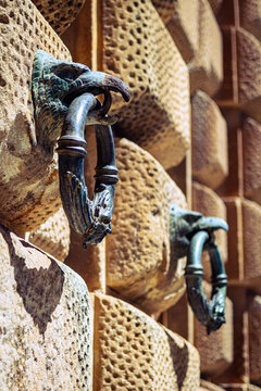 View of weathered stone wall adorned with ornate metal handles, each featuring a unique griffin design, creating a timeless and artistic scene, Alhambra, Andalucia, Spain.