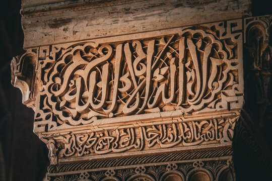 View of intricate Arabic calligraphy adorning a weathered stone column, showcasing the rich artistic heritage, Alhambra, Andalucia, Spain.