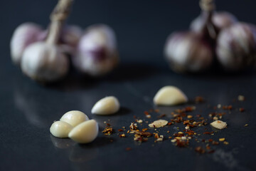 Garlic Cloves with Chili Flakes on Dark Surface &ndash; Shallow Depth of Field