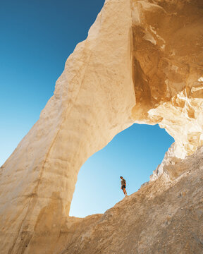 View of the stark white chalk cliffs frame a lone figure against the azure sky, creating a dramatic contrast of color and scale, Aktau, Mangystau Region, Kazakhstan.