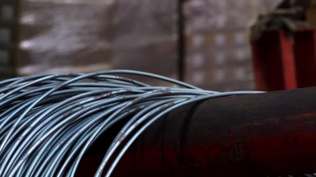 Metal wire spooling process in a dark industrial factory setting