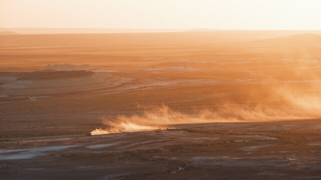 View of sun-drenched landscape where the wind whips across the arid ground, creating a hazy spectacle of motion and light, Kyzylkup, Mangystau Region, Kazakhstan.