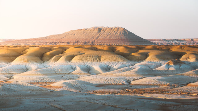 View of layered and textured earth tones paint a canvas of a rugged landscape under a serene sky, Kyzylkup, Mangystau Region, Kazakhstan.