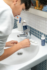 Teenager putting on contact lenses for vision correction in bathroom