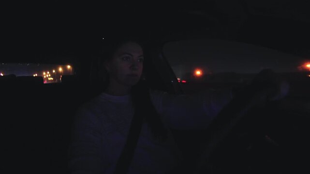 Close view of woman gripping steering wheel at night suggesting tension alertness endurance and disciplined control while traveling alone across illuminated city streets