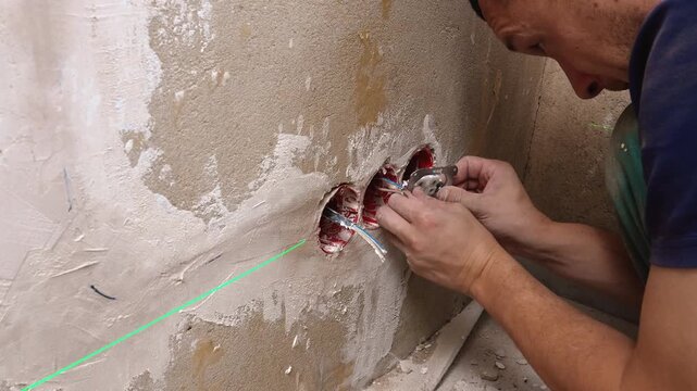 Renovation Worker Accurately Inserting Frames Into Wall Cavities. Artisan Precisely Marks And Positions Electrical Enclosures Within Damaged Plaster Surfaces During Refurbishment