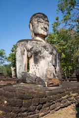 Ancient sculpture of the seated Buddha is close-up. Ruins of Wat Phra Kaeo Buddhist Temple. Kamphaengphet Historical Park, Thailand