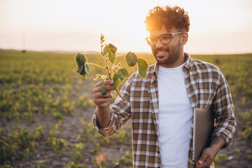 Agronomist Holding Soybean Plant and Laptop at Sunset in Field