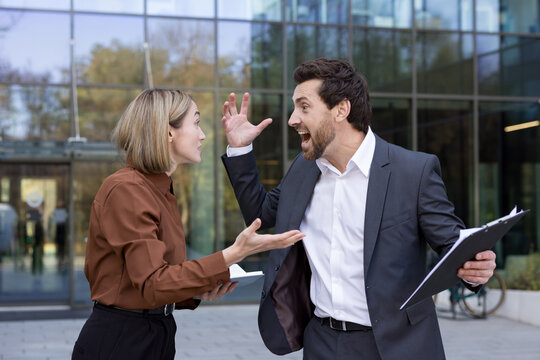 Businesspeople having a heated argument outside modern office building, yelling and expressing frustration during a stressful work conflict, showcasing workplace tension and communication breakdown