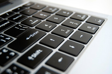 Obraz premium A close-up of a laptop keyboard. Enter key highlighted background. A laptop keys background.