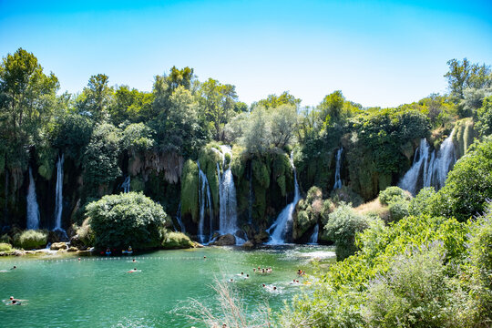 Beautiful view of Kravice Waterfalls in Bosnia and Herzegovina, featuring cascading turquoise waters surrounded by lush green forest. This natural wonder offers a peaceful and refreshing atmosphere, s