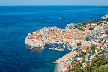 Obraz premium Stunning panoramic view from a Dubrovnik viewpoint overlooking the ancient city walls and the crystal-clear waters of Banje Beach. A perfect capture of Croatia’s coastal charm, blending historic archi