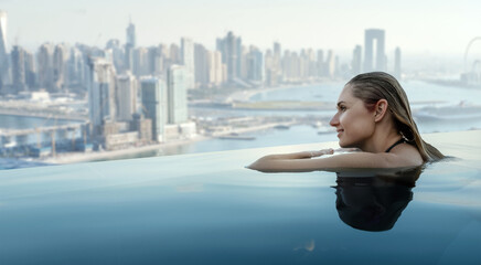 woman enjoying Dubai panorama from rooftop infinity pool. copy space