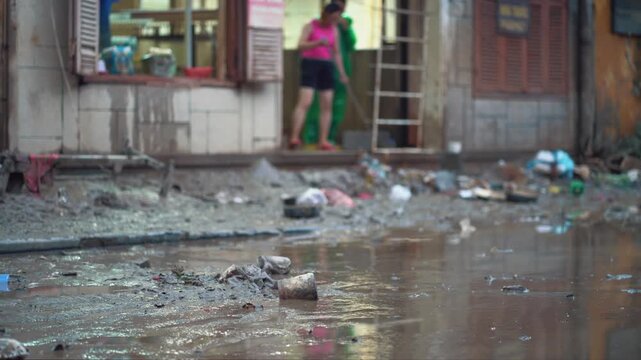person cleaning house from water and mud after flood, woman with mop recover submerged underwater home after flooding, restoration of building after natural disaster, Hoi An Vietnam 4k