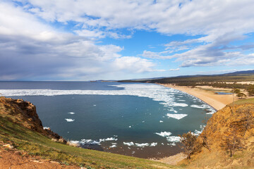 Obraz premium Baikal Lake in springtime. View of the sandy beach of the Sarayskiy bay with melting ice near near the village of Khuzhir. Beautiful spring landscape. Natural background. Spring travels and outdoors