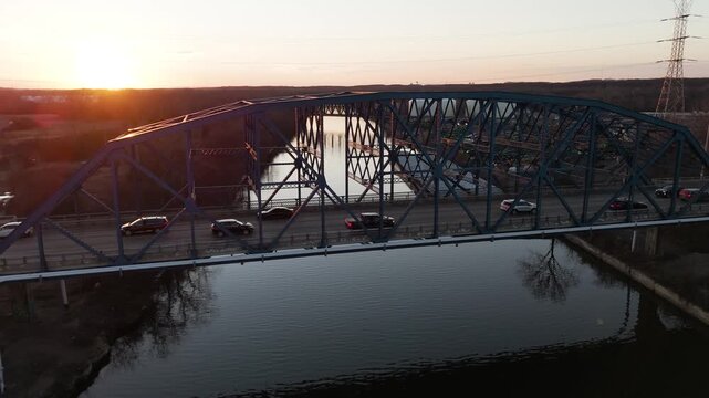 Cinematic Drone View of Cars Crossing Bridge Over River During Golden Hour