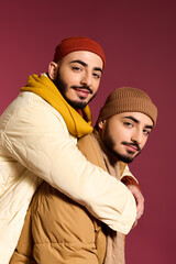 Obraz premium Stylish twins share a warm embrace in trendy winter fashion against a vibrant backdrop