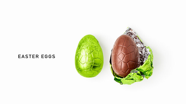 Two chocolate easter eggs, one wrapped in shiny green foil and one partially unwrapped, isolated on white background