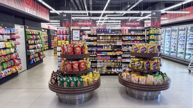 Snack aisle with various chip brands and confectionery in Penang grocery store on April 17, 2025