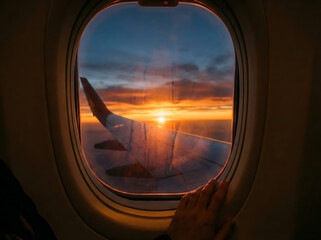 Fototapeta premium View from an airplane window of a stunning sunset over a sea of clouds with the wing visible