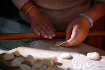 Obraz premium A focused close-up captures a woman's skilled hands shaping dumplings