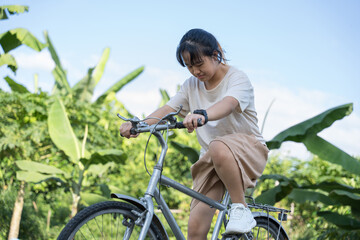 A young girl concentrating while riding a bicycle outdoors in nature.
