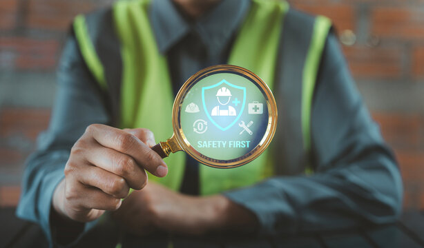 Engineer holding magnifying glass focusing on safety first and zero accident icons for risk inspection concept, Occupational Health and Safety OHS, EHS Environment, Health, and Safety