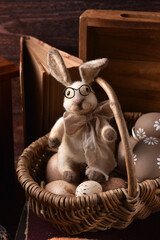 Easter decoration with handicraft bunny sitting in a wicker basket with eggs