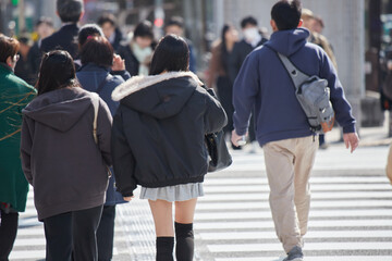 Obraz premium 冬の昼の名古屋の繁華街の横断歩道を渡る若い女性と人々の姿