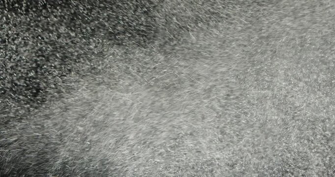 Tiny snow or dust randomly flying in the smoky air, empty space template for objects advertisement. Many dust particles cloud of white powder in low light on empty dark black contrast background.