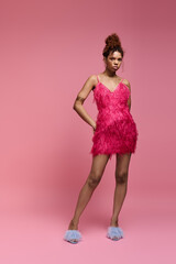 Stylish young woman in vibrant pink attire stands confidently against a soft pink backdrop