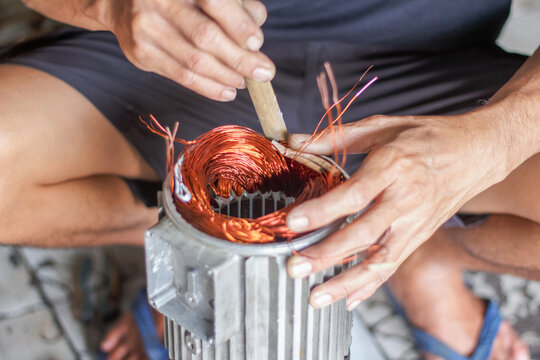 Top view of technician installing copper coil into electric motor.