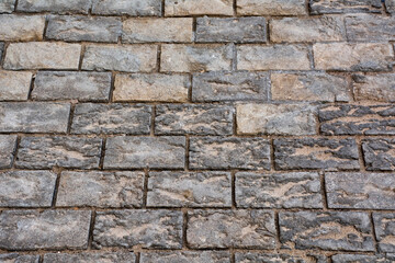 Obraz premium Detailed textured stone pavement background with weathered rectangular cobblestones in neutral grey and beige tones forming a rustic urban pattern ideal for design use.