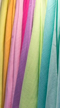  Kolorowe tkaniny wiszące obok siebie, pastelowe materiały na zasłony i ubrania, tekstura i wyb&oacute;r kolor&oacute;w w zbliżeniu.