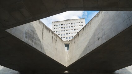 Abstract view of concrete structure framing older building against blue sky
