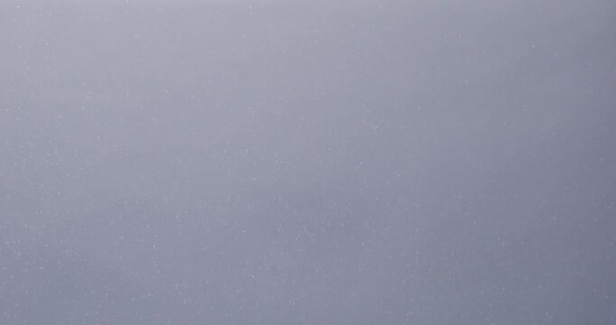 Tiny snow or dust randomly flying in the air, empty space template for objects advertisement. Many dust particles cloud of white powder on empty lit background.